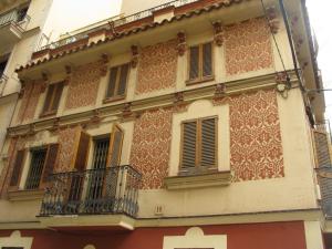 Незабаром по ліву руку бачимо невелике ошатне рожеве будівля, прикрашена візерунками в техніці сграфіто (кут Carrer de Sant Carles і Carrer Grau i Torras)
